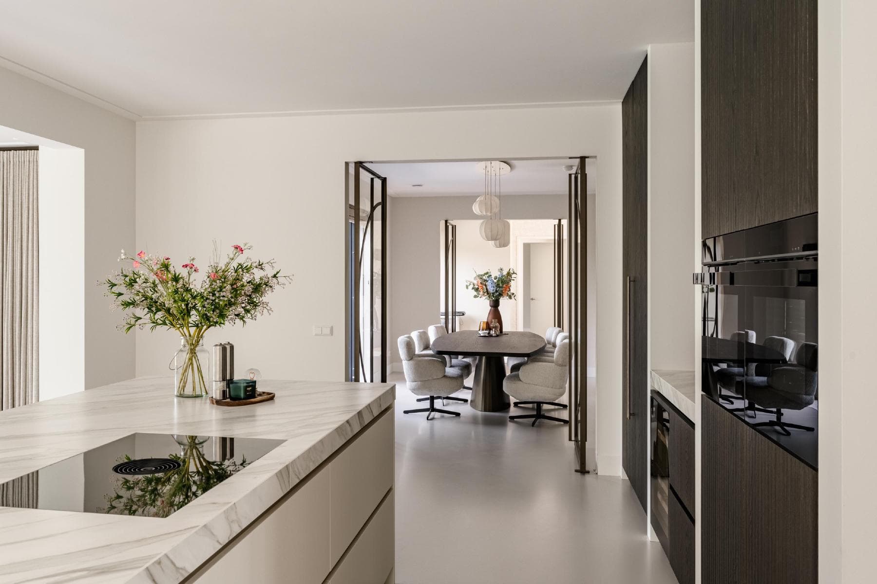 Kitchen with marble island looking into dining room through steel-framed doors
