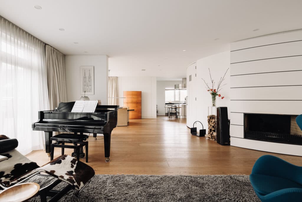 Living room with grand piano, fireplace and garden view