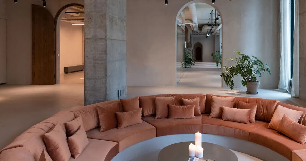 Renessence — curved terracotta sofa beneath arched concrete columns