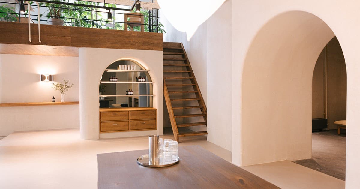 White plastered interior with wooden staircase and arched shelving