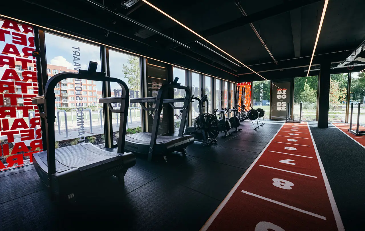 Trainmore Slotervaart — training floor with red track and linear lighting